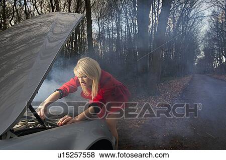 Stock Photo - Woman looking under hood of car. Fotosearch