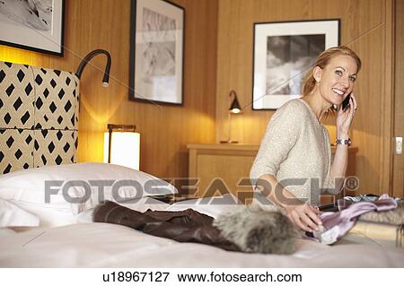 Stock Photo - Woman on cell phone in hotel room. Fotosearch