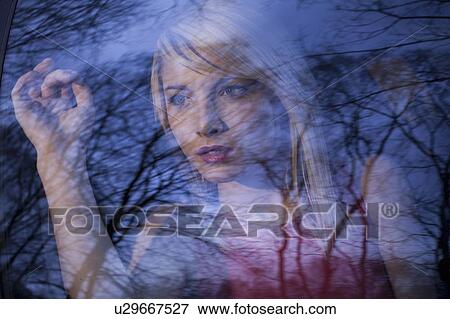 Stock Photo - Woman peering out car window in woods. Fotosearch
