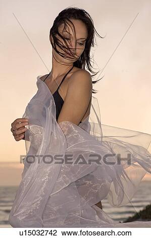 Stock Image - Woman playing with sarong on beach. Fotosearch