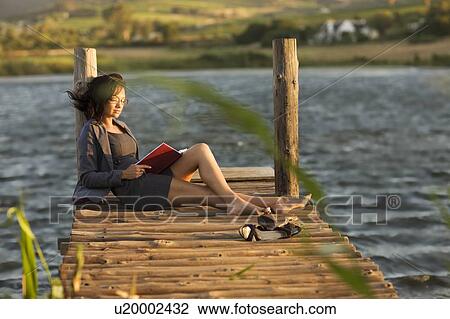 Woman reading book on dock View Large Photo Image Stock Image - Woman reading book on dock. Fotosearch