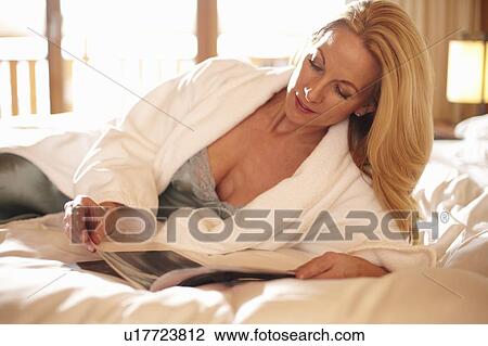 Woman reading magazine on bed View Large Photo Image Stock Image - Woman reading magazine on bed. Fotosearch