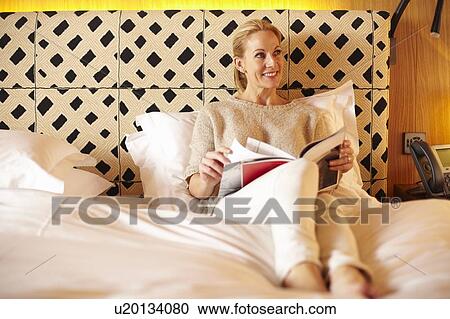 Woman reading magazine on bed View Large Photo Image Stock Image - Woman reading magazine on bed. Fotosearch