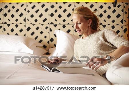 Woman reading magazine on bed View Large Photo Image Stock Photo - Woman reading magazine on bed. Fotosearch