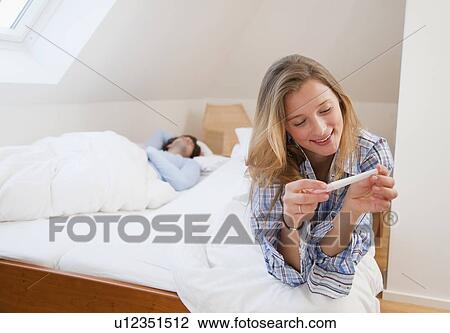 Woman reading pregnancy test on bed View Large Photo Image Stock Image - Woman reading pregnancy test on bed. Fotosearch