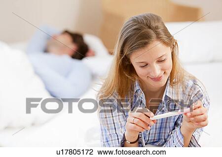 Woman reading pregnancy test on bed View Large Photo Image Stock Image - Woman reading pregnancy test on bed. Fotosearch