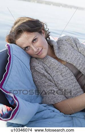 Picture - Woman relaxing in boat on still lake. Fotosearch