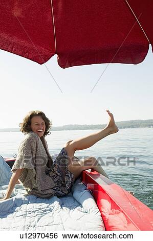 Woman relaxing in boat on still lake View Large Photo Image Stock Photograph - Woman relaxing in boat on still lake. Fotosearch