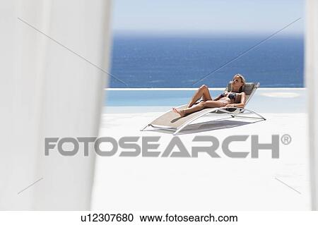 Woman relaxing in lawn chair by pool View Large Photo Image Stock Image - Woman relaxing in lawn chair by pool. Fotosearch
