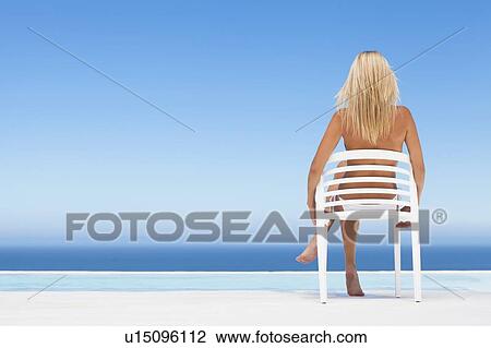 Woman relaxing in lawn chair by pool View Large Photo Image Stock Image - Woman relaxing in lawn chair by pool. Fotosearch