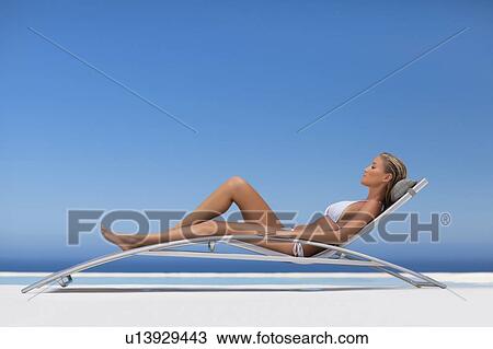 Woman relaxing in modern chair by pool View Large Photo Image Stock Image - Woman relaxing in modern chair by pool. Fotosearch