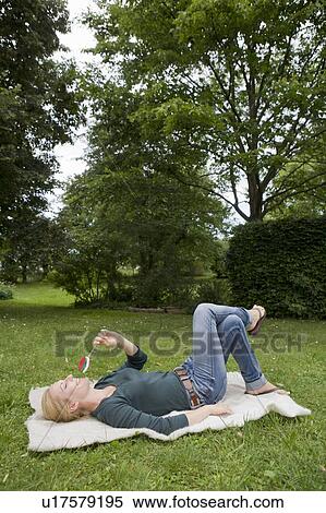 Woman relaxing on blanket in grass View Large Photo Image Stock Photography - Woman relaxing on blanket in grass. Fotosearch