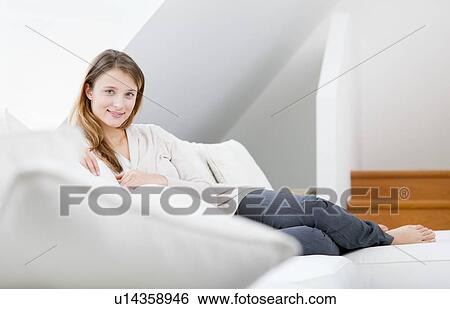 Woman relaxing on sofa in living room View Large Photo Image Stock Photograph - Woman relaxing on sofa in living room. Fotosearch