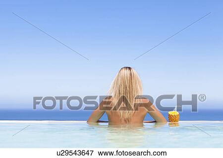 Stock Photo - Woman relaxing with drink in pool. Fotosearch