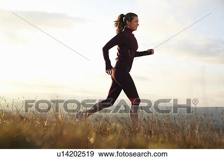 Stock Photo - Woman running in rural field. Fotosearch