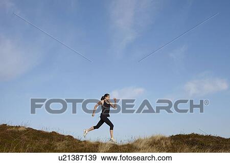 Stock Photo - Woman running on rural hillside. Fotosearch