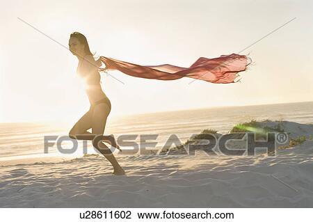 Woman running with sarong on beach View Large Photo Image Stock Image - Woman running with sarong on beach. Fotosearch