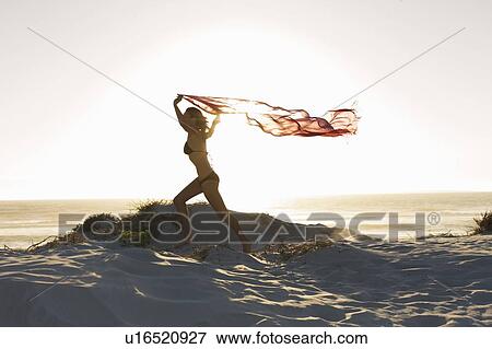 Stock Photo - Woman running with sarong on beach. Fotosearch
