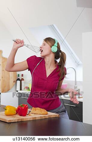 Stock Photograph - Woman singing with whisk in kitchen. Fotosearch