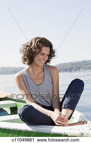 Woman sitting in boat in still lake View Large Photo Image Stock Image - Woman sitting in boat in still lake. Fotosearch
