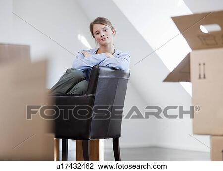 Stock Image - Woman sitting in chair in new house. Fotosearch