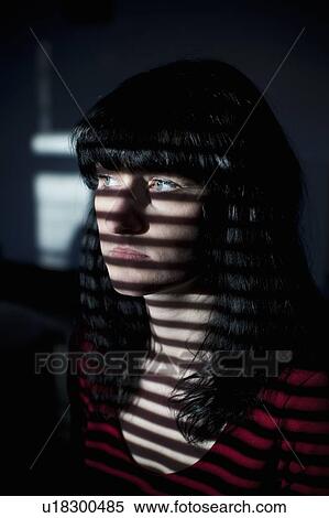 Stock Photography - Woman standing in blinds shadow. Fotosearch