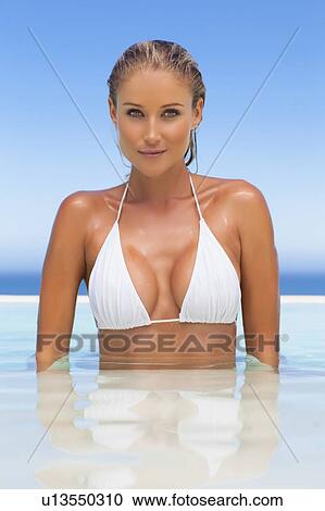Stock Image - Woman standing in infinity pool. Fotosearch