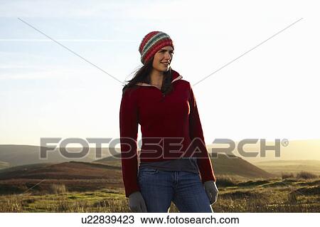Stock Image - Woman standing in rural field. Fotosearch