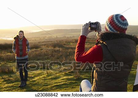 Woman taking picture of friend outdoors View Large Photo Image Stock Image - Woman taking picture of friend outdoors. Fotosearch