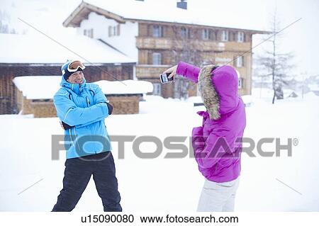 Woman taking picture of husband in snow View Large Photo Image Stock Image - Woman taking picture of husband in snow. Fotosearch