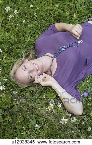 Woman talking on cell phone in grass View Large Photo Image Stock Photography - Woman talking on cell phone in grass. Fotosearch