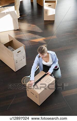 Picture - Woman taping up cardboard box. Fotosearch