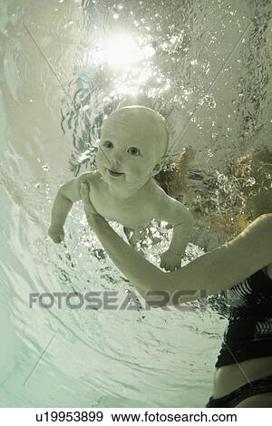 Stock Photo - Woman teaching baby to swim in pool. Fotosearch