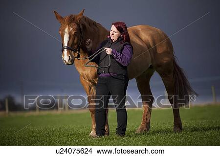 Picture - Woman walking horse in rural field. Fotosearch