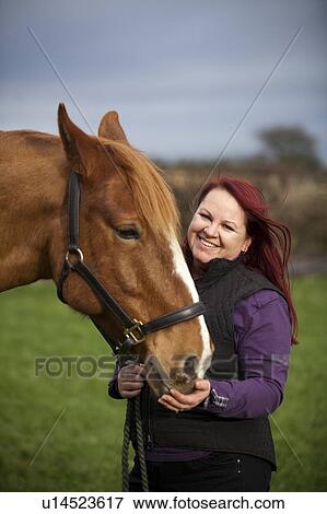 Stock Photo - Woman walking horse in rural field. Fotosearch