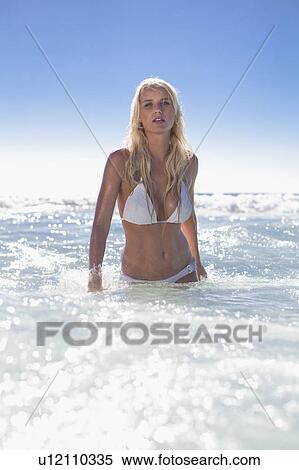 Stock Photography - Woman walking in waves on beach. Fotosearch
