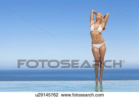Woman wearing bikini by infinity pool View Large Photo Image Stock Image - Woman wearing bikini by infinity pool. Fotosearch