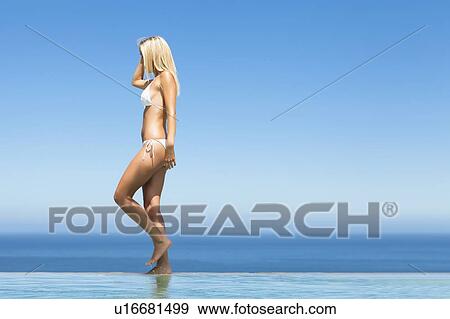 Stock Photo - Woman wearing bikini by infinity pool. Fotosearch