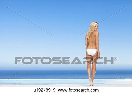 Woman wearing bikini by infinity pool View Large Photo Image Stock Photo - Woman wearing bikini by infinity pool. Fotosearch