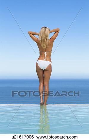 Woman wearing bikini by infinity pool View Large Photo Image Stock Photograph - Woman wearing bikini by infinity pool. Fotosearch