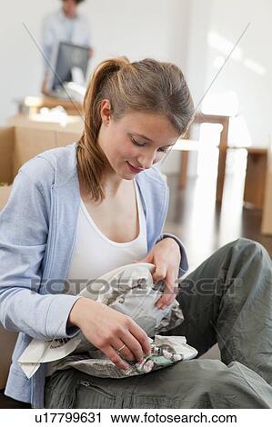 Stock Image - Woman wrapping up dishes to pack. Fotosearch