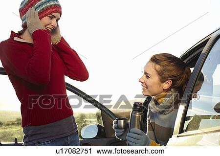 Stock Image - Women drinking coffee from thermos. Fotosearch