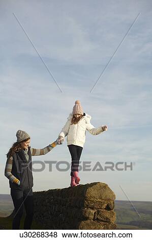 Women helping daughter balance on wall View Large Photo Image Stock Photo - Women helping daughter balance on wall. Fotosearch