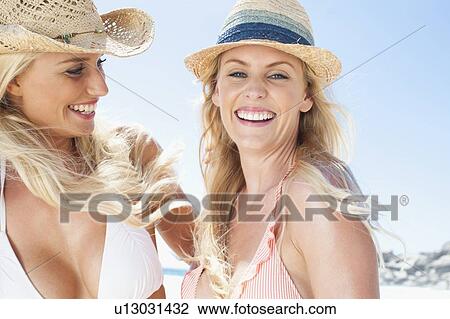 Stock Image - Women laughing together on beach. Fotosearch