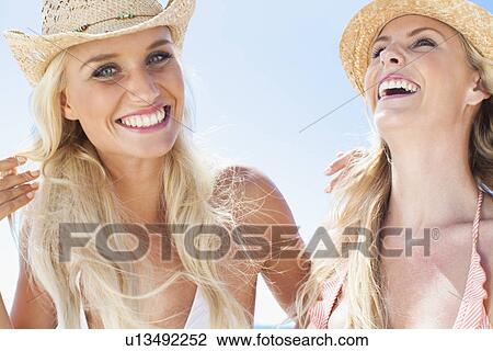 Stock Image - Women laughing together on beach. Fotosearch