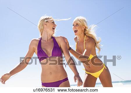 Stock Image - Women laughing together on beach. Fotosearch