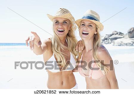 Stock Image - Women laughing together on beach. Fotosearch