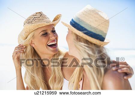Stock Photo - Women laughing together on beach. Fotosearch