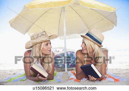 Women relaxing under umbrella on beach View Large Photo Image Stock Image - Women relaxing under umbrella on beach. Fotosearch