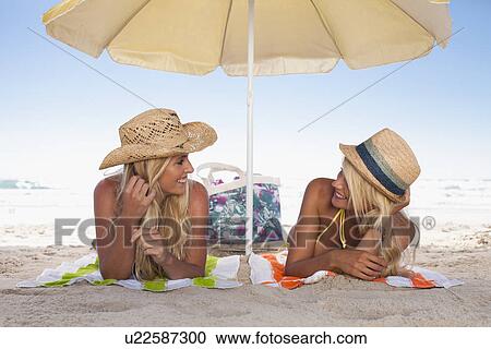 Women relaxing under umbrella on beach View Large Photo Image Stock Image - Women relaxing under umbrella on beach. Fotosearch